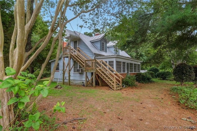 rear view of property featuring cooling unit, metal roof, stairs, and a sunroom