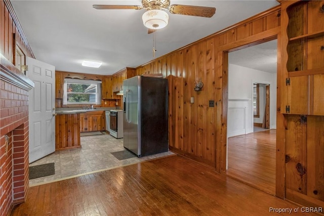 kitchen with brown cabinets, light wood-style flooring, stainless steel refrigerator with ice dispenser, a fireplace, and gas range