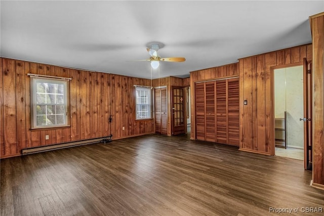 spare room featuring a ceiling fan, a healthy amount of sunlight, wood finished floors, and a baseboard radiator