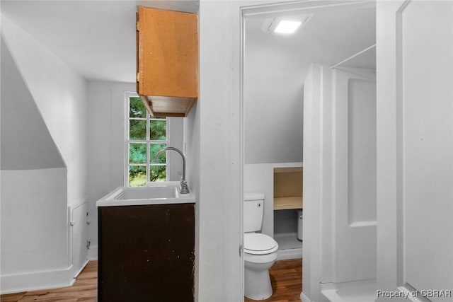 bathroom with toilet, wood finished floors, baseboards, and a sink