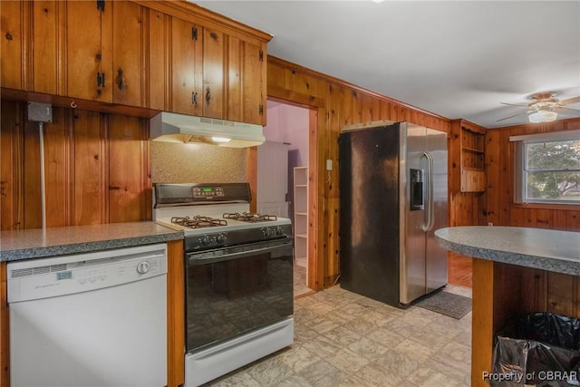 kitchen featuring wooden walls, stainless steel fridge with ice dispenser, under cabinet range hood, dishwasher, and gas range oven