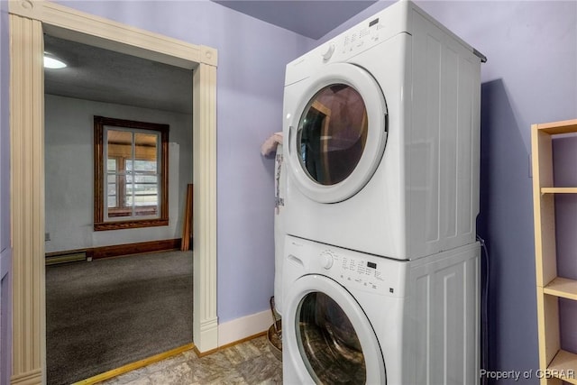 clothes washing area featuring baseboards, stacked washer and dryer, and laundry area