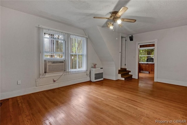 interior space featuring baseboards, heating unit, a textured ceiling, and light wood-style flooring