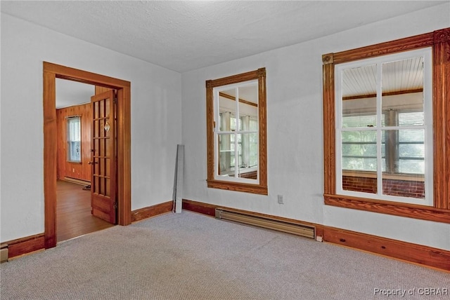 carpeted spare room with a baseboard heating unit, baseboards, baseboard heating, and a textured ceiling