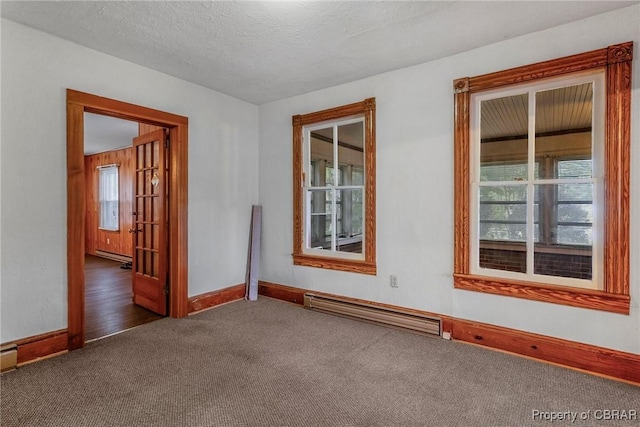 unfurnished room featuring carpet flooring, a healthy amount of sunlight, baseboard heating, and a textured ceiling