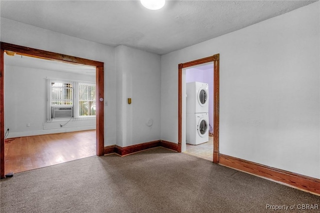 spare room with cooling unit, baseboards, stacked washer and clothes dryer, and carpet floors