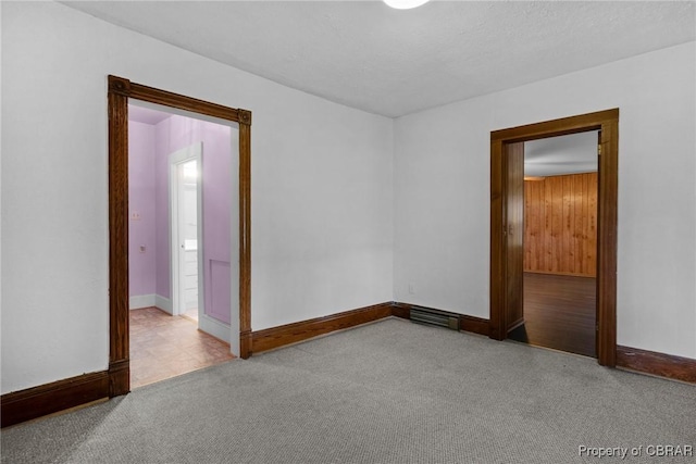 spare room with carpet flooring, visible vents, and baseboards