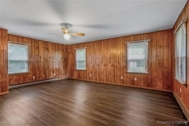 empty room with baseboards, baseboard heating, wood finished floors, and a ceiling fan