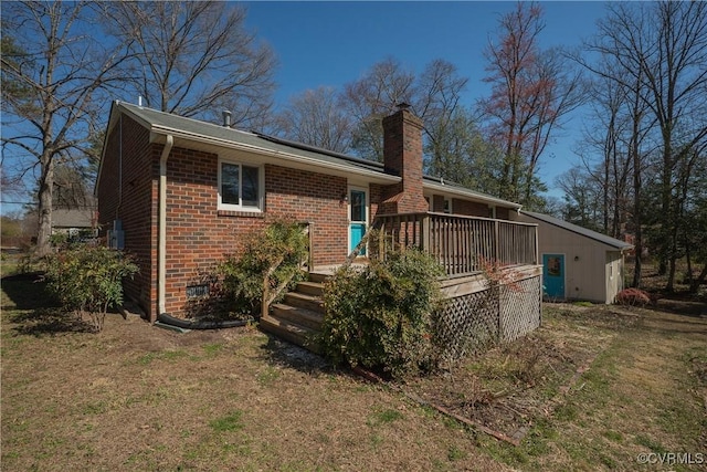 back of house with a yard, brick siding, a deck, and a chimney