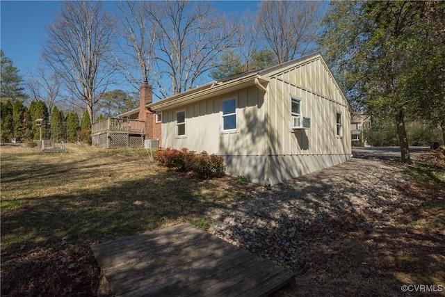 view of property exterior with a wooden deck, a lawn, board and batten siding, and a chimney