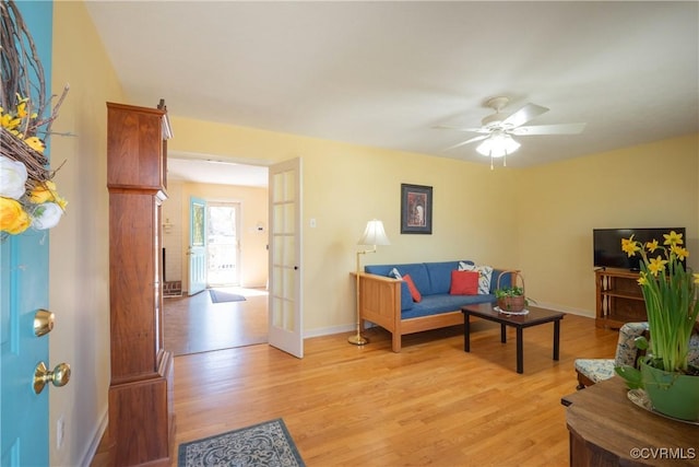 living room with a ceiling fan, light wood-style floors, and baseboards