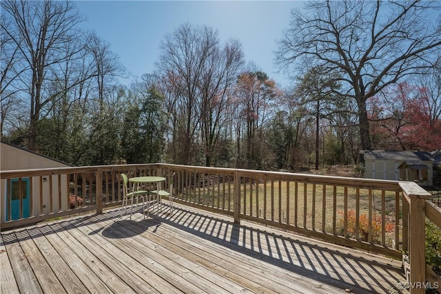 wooden terrace featuring an outdoor structure and a shed