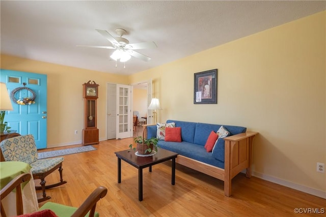 living room with french doors, baseboards, light wood-style floors, and ceiling fan