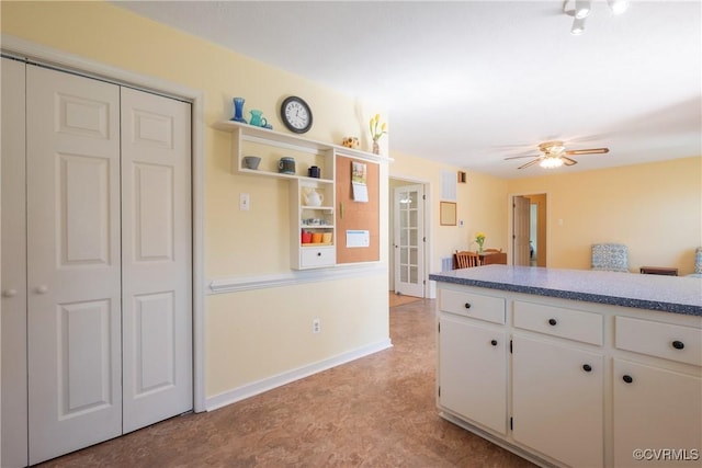 kitchen featuring baseboards, ceiling fan, and white cabinetry