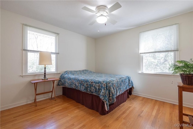 bedroom with multiple windows, baseboards, and light wood-style floors