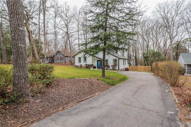 view of front of house featuring aphalt driveway, a front yard, and fence