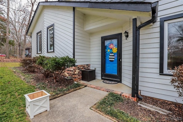 view of exterior entry with a yard and brick siding