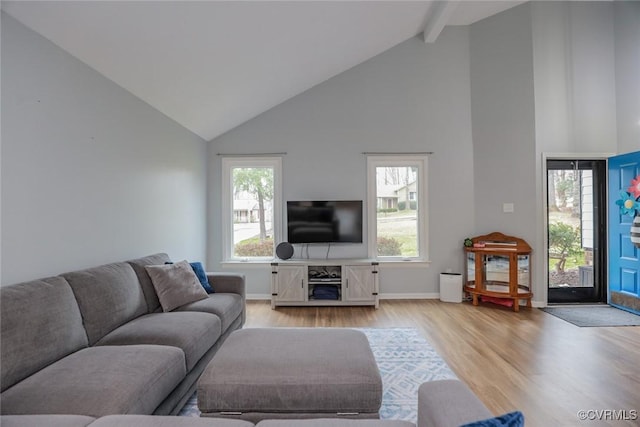 living room featuring baseboards, plenty of natural light, beam ceiling, and light wood finished floors