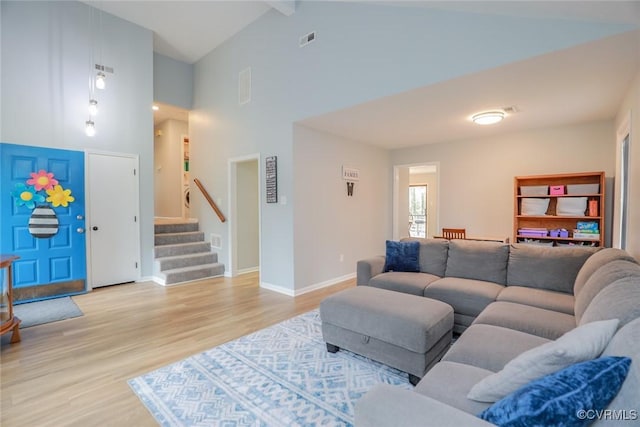 living room with baseboards, visible vents, high vaulted ceiling, stairs, and light wood-style floors