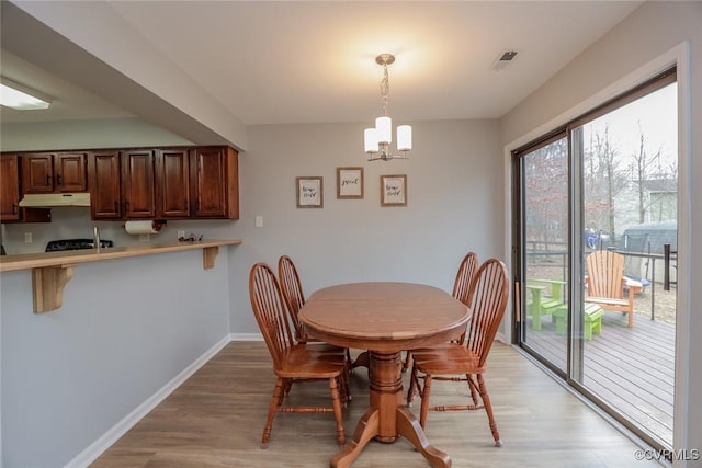 dining space featuring visible vents, baseboards, a chandelier, and light wood finished floors