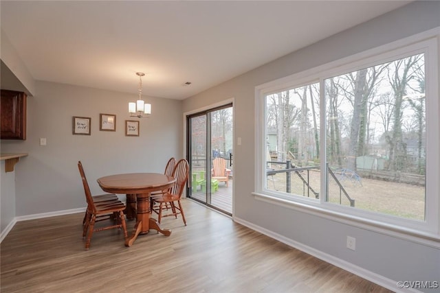 dining area featuring a notable chandelier, baseboards, and light wood-style floors