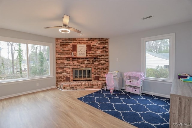 game room featuring visible vents, a ceiling fan, wood finished floors, a fireplace, and baseboards