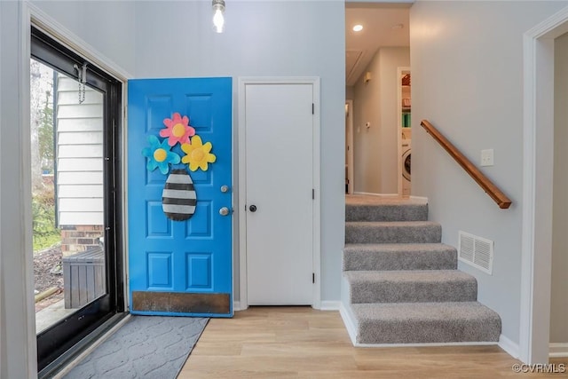 foyer with visible vents, wood finished floors, baseboards, washer / dryer, and stairs