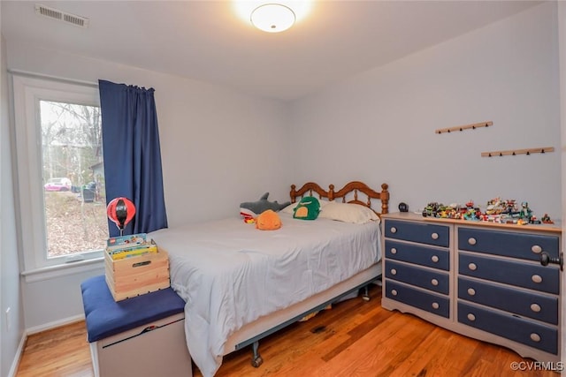 bedroom with visible vents, baseboards, and wood finished floors