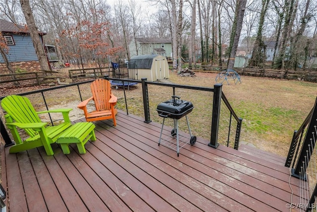 wooden deck featuring a shed, a yard, an outdoor structure, grilling area, and a trampoline