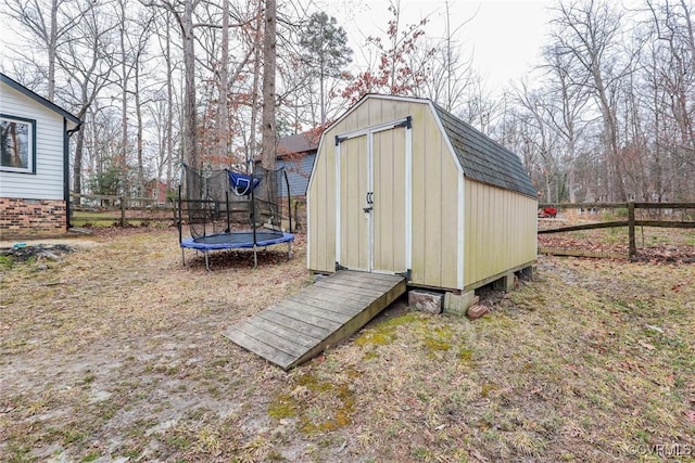 view of shed with a trampoline and fence