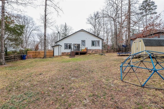 rear view of house featuring a fenced backyard, a trampoline, an outdoor structure, and a storage shed