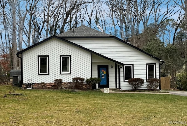 view of front facade with central air condition unit, a front yard, and a shingled roof