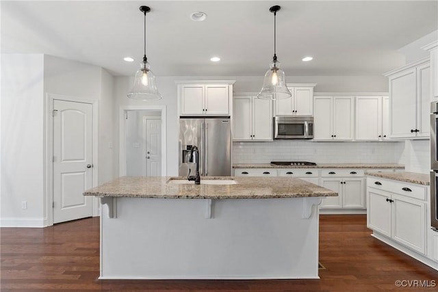 kitchen featuring an island with sink, a sink, dark wood-style floors, appliances with stainless steel finishes, and white cabinets