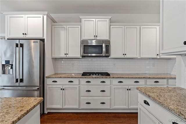 kitchen with light stone counters, backsplash, appliances with stainless steel finishes, and white cabinets