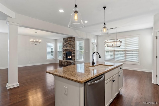 kitchen with dishwasher, decorative columns, a stone fireplace, dark wood-style floors, and a sink