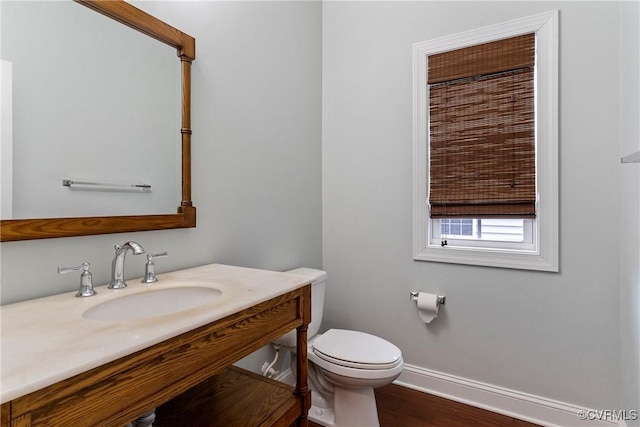 bathroom with a sink, baseboards, toilet, and wood finished floors