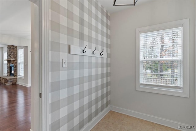 mudroom with tile patterned floors, a fireplace, and baseboards