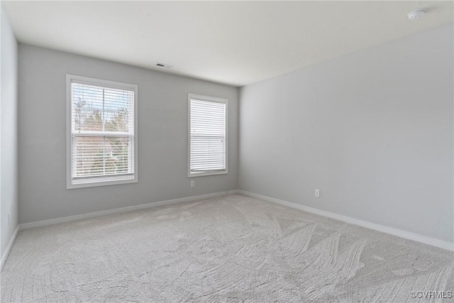 empty room with light carpet, visible vents, and baseboards