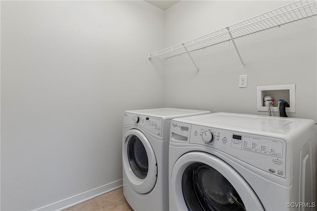laundry room with washer and dryer, baseboards, light tile patterned flooring, and laundry area