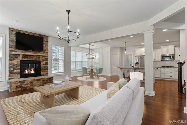 living area featuring a fireplace, dark wood-style flooring, ornate columns, and baseboards