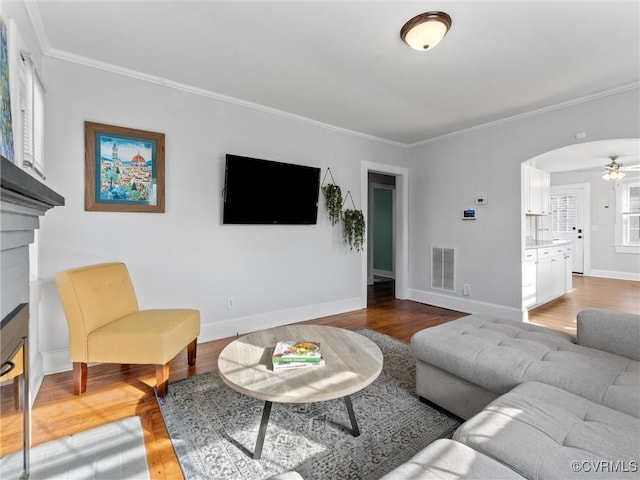 living area with visible vents, ornamental molding, and wood finished floors