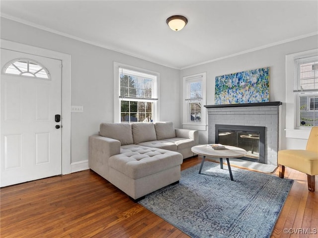 living room featuring hardwood / wood-style flooring, a brick fireplace, crown molding, and baseboards