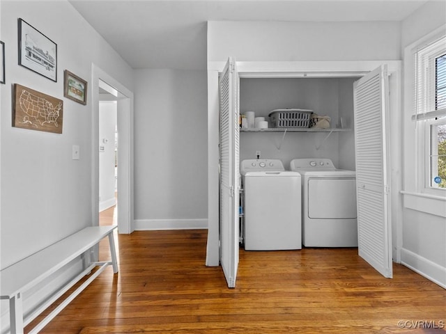 washroom featuring washer and dryer, baseboards, wood finished floors, and laundry area