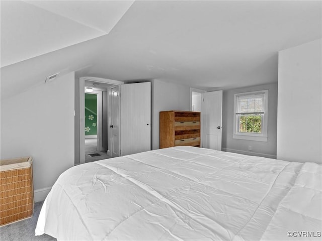 bedroom with visible vents, lofted ceiling, and carpet flooring