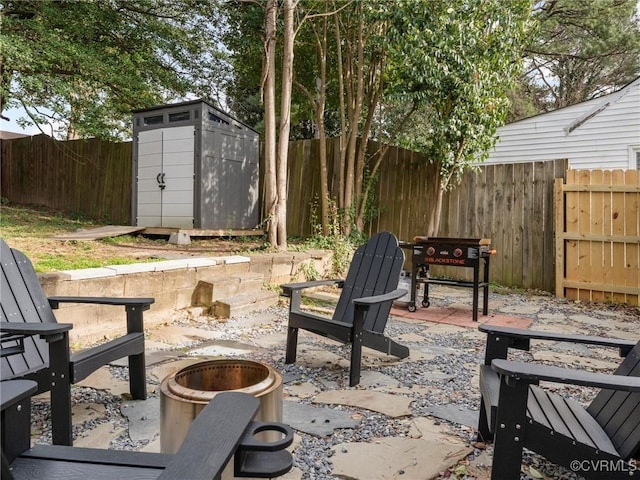 view of patio / terrace with grilling area, a fire pit, a storage shed, an outdoor structure, and a fenced backyard