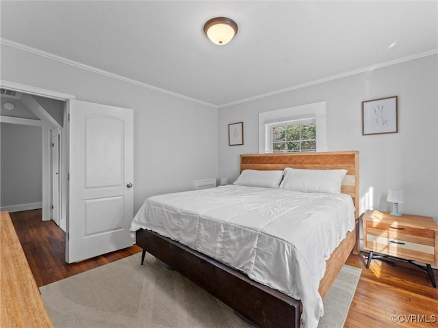 bedroom with visible vents, ornamental molding, and wood finished floors