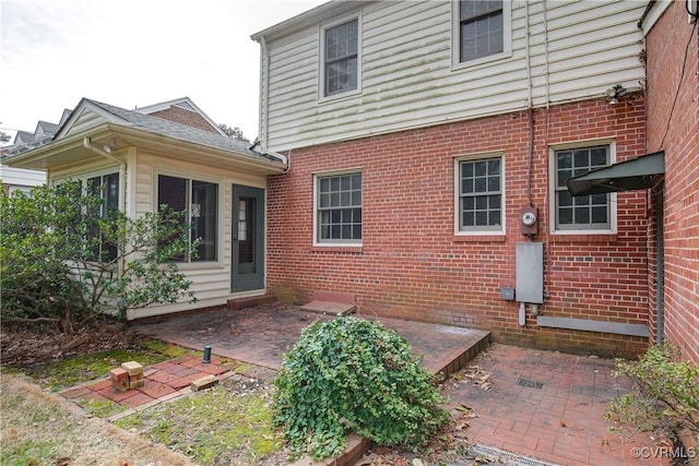 rear view of property featuring brick siding and a patio area