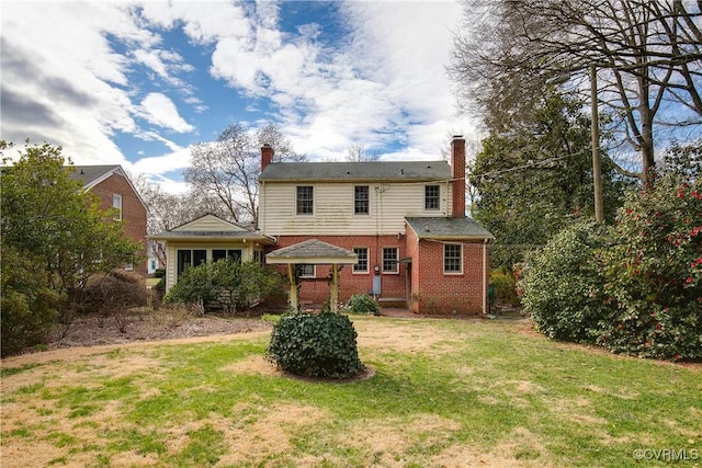 rear view of property featuring brick siding, a chimney, and a yard