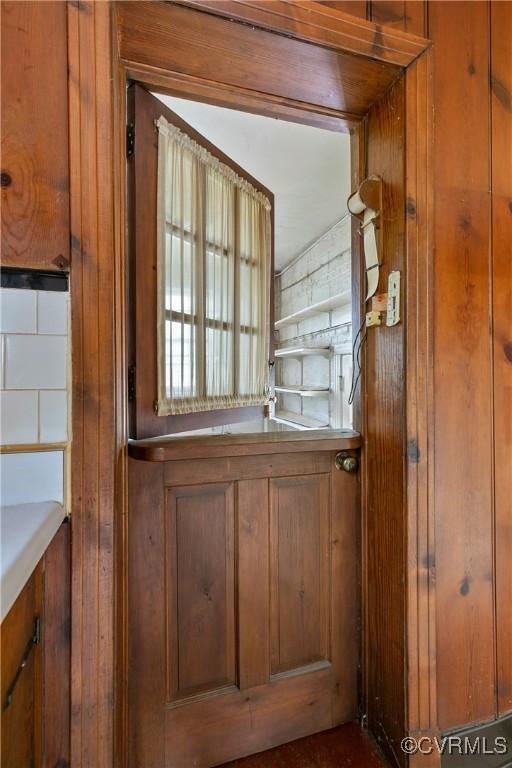 interior space with light countertops, brown cabinetry, and wood walls