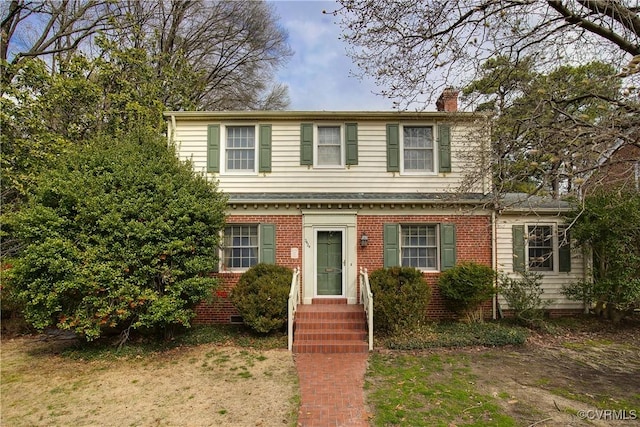 view of front facade with brick siding and a chimney